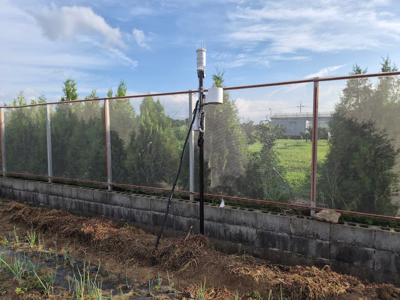 An outdoor weather station and logger record environmental conditions near the field boundary.