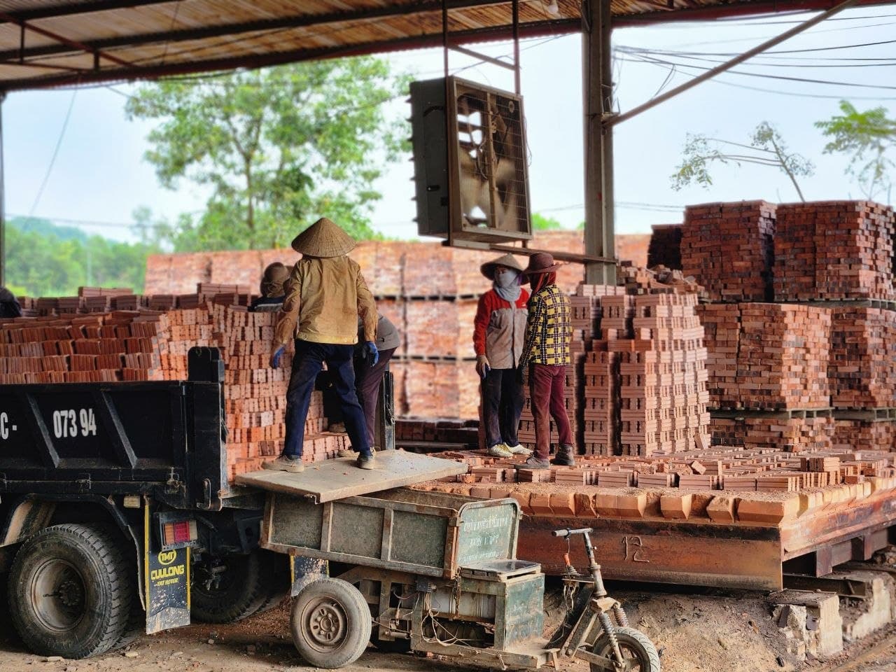 Workers load finished bricks for movement from the production site.